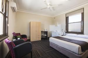 a hotel room with a bed, chair, and a television at Toongabbie Hotel in Blacktown