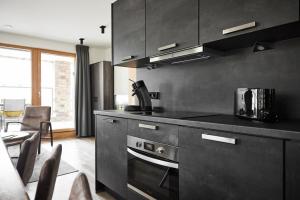a kitchen with black cabinets and a stove top oven at Camp Exklusiv - Alpin-Resort Montafon Haus 2 by Pferd auf Wolke in Gargellen