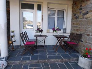 a patio with two tables and chairs and a window at Chaleureuse maison bretonne in Pleubian