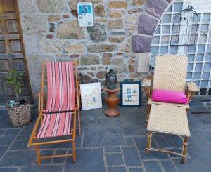 two chairs sitting next to a stone wall with pictures at Chaleureuse maison bretonne in Pleubian