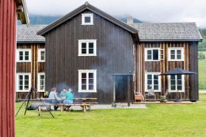dos personas sentadas en un banco frente a una casa en Romsdal Lodge Tømmerhuset, en Isfjorden 12 fotos más