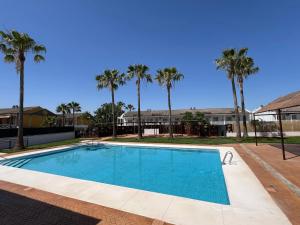 a swimming pool with palm trees in the background at Hospedium Hotel Sky Blu Torre de Sevilla in Torre de la Reina