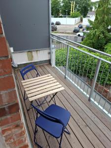 un tavolo in legno e una sedia blu sul balcone. di CityOase Magdeburg Studios am Königsweg, Studio 4, WiFi, Stellplatz, Netflix a Magdeburgo