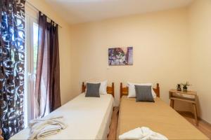 two beds in a room with a window at Villa Angelique in Sinarádes