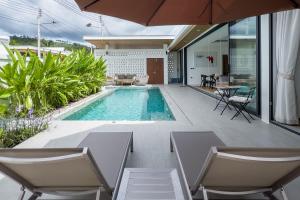 an indoor swimming pool with two chairs and an umbrella at Stephanie villa by fisherman Village in Nathon Bay +4 photos