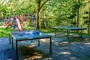 two ping pong tables in front of a playground at Camping Bedura Park in Era Bordeta