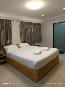 una camera da letto con un letto grande con lenzuola bianche di Arasan Residency a Kotagiri
