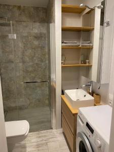 a bathroom with a shower and a sink and a washing machine at West Station Apartment in Warsaw