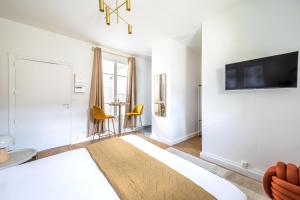 a living room with white walls and a tv on a wall at Studio proche Paris Expo Porte de Versailles in Issy-les-Moulineaux