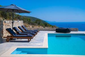 a group of lounge chairs and an umbrella next to a swimming pool at Lefkadian Gem Villas in Áyios Nikólaos Nirás