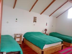 two beds in a room with green sheets at Ecolodge El descanso in Comunidad Yumani
