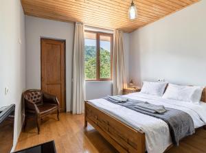 una camera da letto con un letto, una sedia e una finestra di Guest House Nikala a Mestia