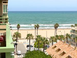 una vista di una spiaggia con palme e l'oceano di Stylish well-connected beachfront flat a Valencia