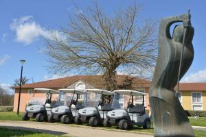 Un grupo de carros de golf estacionados frente a una casa. en Best Western Golf d'Albon, en Albon