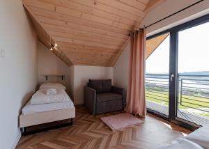 a bedroom with a bed and a chair and a window at Domek u Chmielaków-Huba z widokiem na Jezioro Czorsztyńskie Tatry Balia in Huba