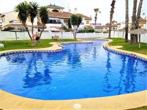 a man standing next to a large blue swimming pool at Chalet adosado en RIOMAR-3, urbanización residencial privada in La Horadada