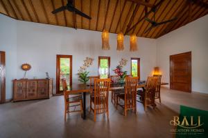 a dining room with a wooden table and chairs at Villa Linggah Longgah, Bali - Spectacular Clifftop Elegance! in Panji