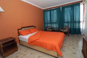 una camera con un letto arancione e un tavolo di Big Bang Hôtel Behoririka a Antananarivo