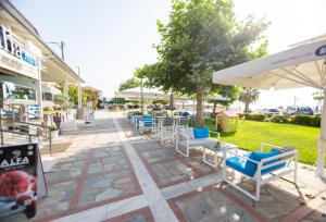 Un patio con sillas y mesas y una sombrilla. en Amalia Mare Sea View, en Nea Vrasna