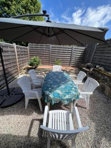 a patio with a table and chairs and an umbrella at Gîte en Bretagne Sud Ty Nikolaz in Sainte-Marie