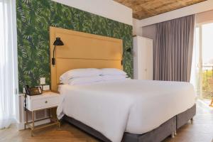 巴兰基亚Faranda Collection Barranquilla, a member of Radisson Individuals的卧室设有一张白色大床和绿色的墙壁