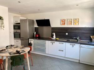 a kitchen with white cabinets and a table with chairs at Chez Marcel - Maison agréable in Dunkerque