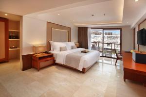 a bedroom with a large bed and a balcony at The Bandha Hotel & Suites in Legian