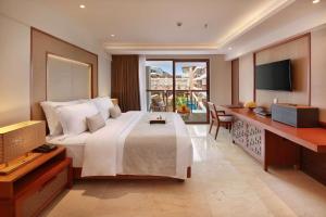 a bedroom with a bed and a desk and a television at The Bandha Hotel & Suites in Legian