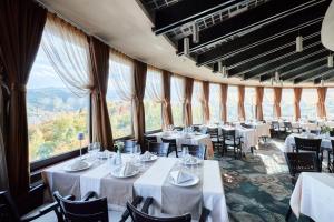 a restaurant with white tables and chairs and large windows at Grand Hotel Belvedere in Braşov