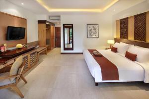 une chambre d'hôtel avec un grand lit et une télévision dans l'établissement Bali Niksoma Boutique Beach Resort, à Legian