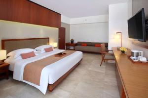 a hotel room with a large bed and a couch at The Magani Hotel and Spa in Legian