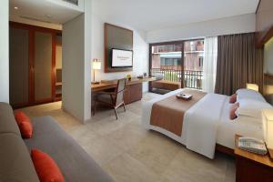 a hotel room with a large bed and a desk at The Magani Hotel and Spa in Legian