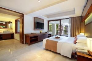 a hotel room with a bed and a television at The Magani Hotel and Spa in Legian