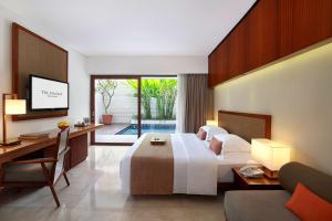 a hotel room with a bed and a desk and a television at The Magani Hotel and Spa in Legian +37 photos