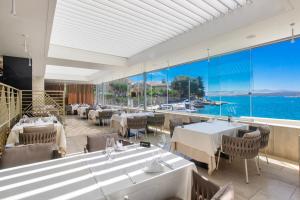 a restaurant with tables and chairs and a view of the water at Pansion Zlatna ribica in Brodarica