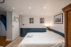 ein Schlafzimmer mit einem großen weißen Bett und einigen Bildern an der Wand in der Unterkunft My Little House in Paris * Hypercentre * Climatisé in Paris