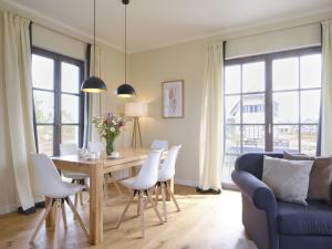 a dining room table with white chairs and a blue couch at Reetland am Meer Premium Reetdachvilla mit 3 Schlafzimmern, Sauna und Kamin H13 in Dranske