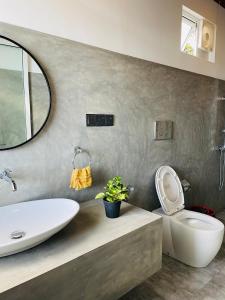 a bathroom with a sink and a toilet and a mirror at Cozy Homestay in Ella