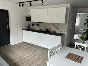 a kitchen with white cabinets and a table and a dining room at Apartamenty Kowary Centrum in Kowary
