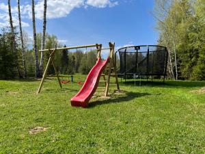 a playground with a red slide in the grass at Metsalagendik Apartments in Otepää
