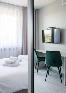 a bedroom with a desk and a bed with a green chair at RentPlanet - Apartamenty Pileckiego in Warsaw