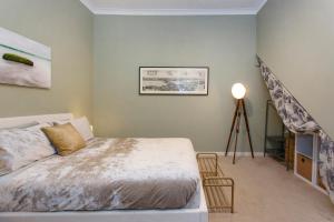ein Schlafzimmer mit einem Bett und einem Treppenaufgang in der Unterkunft Lillys Cottage Heritage House South Fremantle in South Fremantle