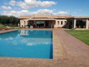 a house with a swimming pool in front of a house at Domaine Lamrah in Marrakesh