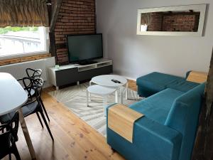 a living room with a blue couch and a tv at Apartamenty Kowary Centrum in Kowary