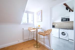 a kitchen with a table and two stools at Studio coloré proche Paris Parc des Princes in Issy-les-Moulineaux