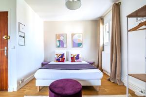 a bedroom with a large bed with a purple stool at Studio coloré proche Paris Parc des Princes in Issy-les-Moulineaux