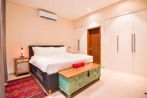 a bedroom with a large white bed and a wooden bench at Villa Palmview in Salalah +25 photos