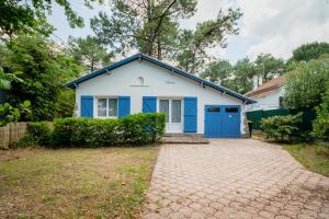 a white house with blue doors and a driveway at Villa L'Herbaudière - La Baule les Pins in La Baule