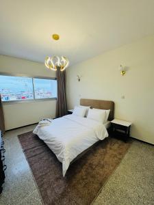 a bedroom with a large white bed and a chandelier at Appartement spacieux - BD Anfa in Casablanca