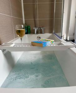 a glass of wine sitting on a bath tub with a glass of wine at Clock Tower Apartment No4 in Morecambe